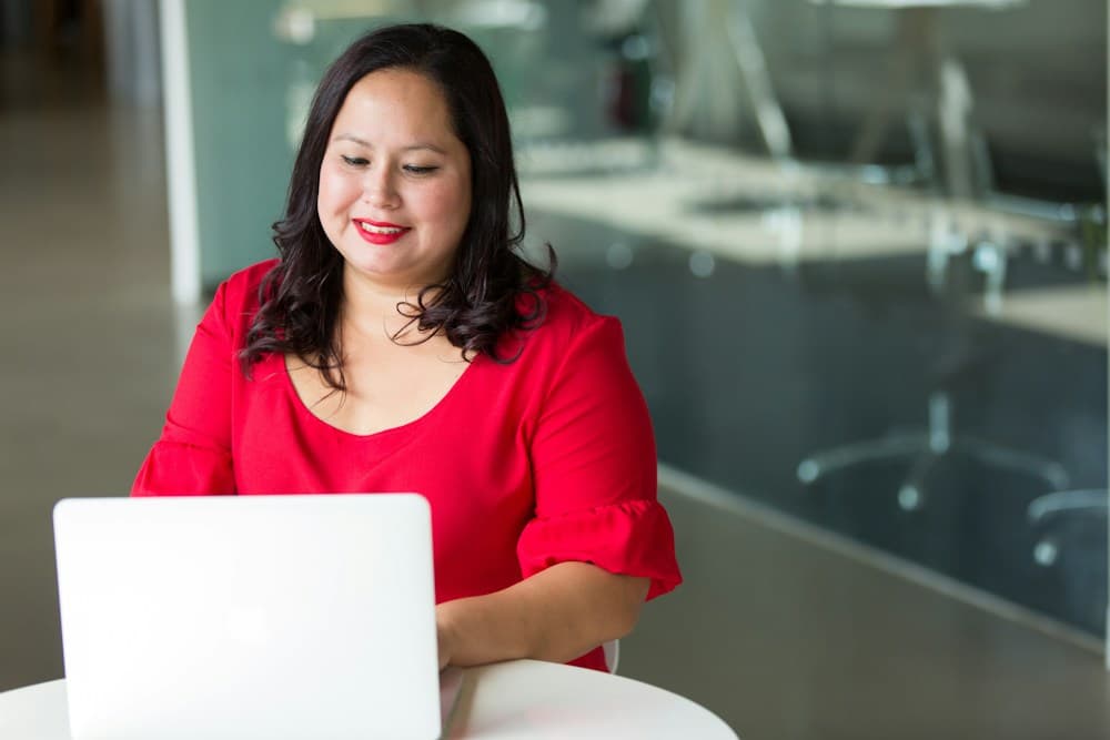 A woman smiling while working on her laptop